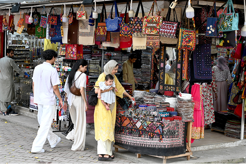 Visitors looking for handmade embroideries at a stall setup in Lok Virsa