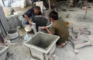 Labourers make cement plants pots for gardening at their work place near Shahdara Marble Market