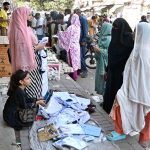 A woman sells school uniforms at a roadside stall in Shah Alami Chowk