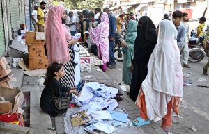 A woman sells school uniforms at a roadside stall in Shah Alami Chowk