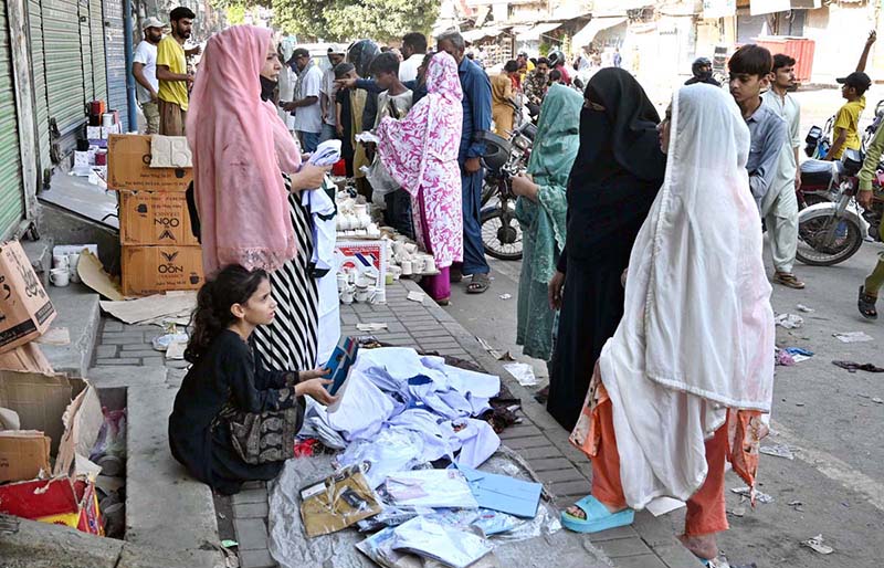 A woman sells school uniforms at a roadside stall in Shah Alami Chowk