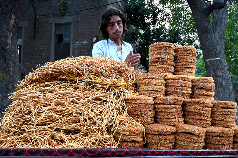 A street vendor arranging and displaying the snacks on his hand cart to attract the customers on their handcart at the roadside setup
