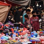 A woman shops for lunchboxes and slippers for her children at Naulakha Bazaar