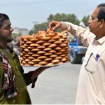 A vendor sells traditional sweet food items at Qambar Road