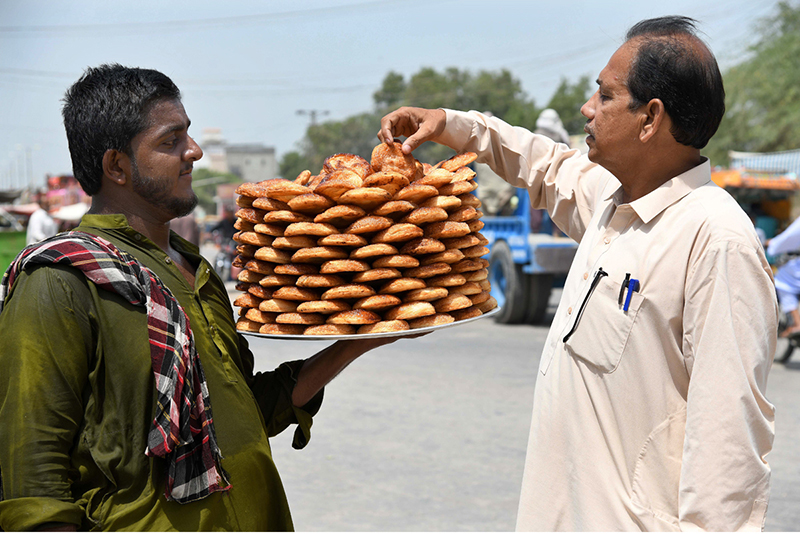 A vendor sells traditional sweet food items at Qambar Road