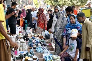 A woman sells school uniforms at a roadside stall in Shah Alami Chowk