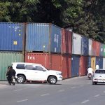 Commuters ride past shipping containers stacked in front of Serena Hotel as authorities beef up security ahead of PTI's expected long march