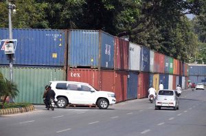 Commuters ride past shipping containers stacked in front of Serena Hotel as authorities beef up security ahead of PTI's expected long march