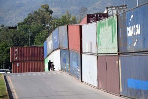 Commuters ride past shipping containers stacked in front of Serena Hotel as authorities beef up security ahead of PTI's expected long march