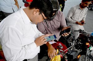 A petrol pump employee verifies a token number from mobile message presented by a motorist to confirm eligibility for subsidized fuel under the Prime Minister’s petrol relief package
