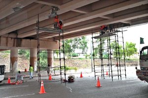 Labourers repair and paint the underside of an overpass along GT Road near Srinagar Highway in the Federal Capital.