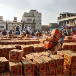 Vendors display crates of tomatoes during an auction as shopkeepers participate in bidding at a local vegetable market