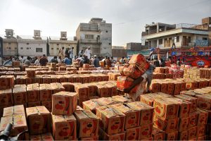 Vendors display crates of tomatoes during an auction as shopkeepers participate in bidding at a local vegetable market