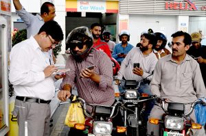 A petrol pump employee verifies a token number from mobile message presented by a motorist to confirm eligibility for subsidized fuel under the Prime Minister’s petrol relief package