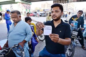 A motorcyclist shows the token to a petrol pump attendant under the Prime Minister’s Fuel Relief Scheme to receive subsidized petrol in Latifabad.