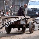 Labourers load iron rods onto a handcart for delivery to a local market in the provincial capital
