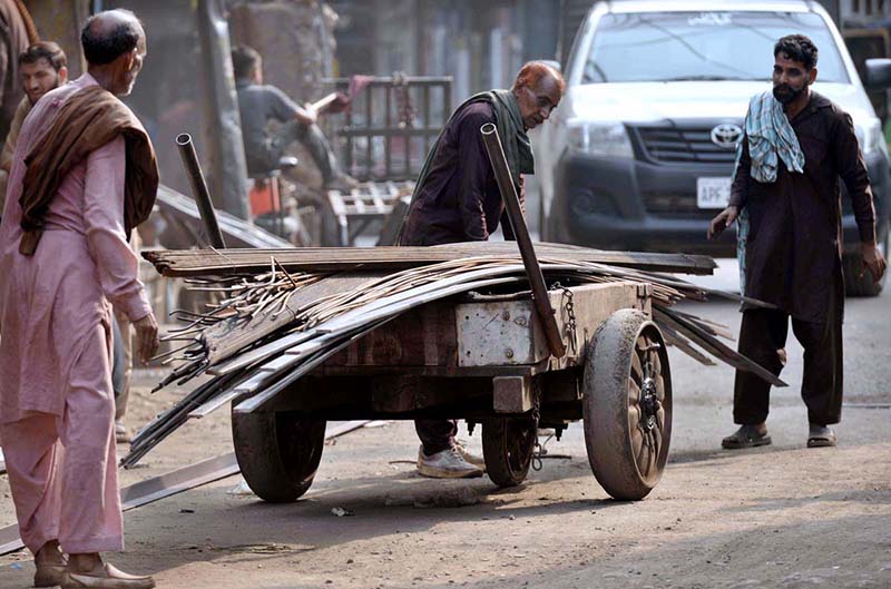 Labourers load iron rods onto a handcart for delivery to a local market in the provincial capital