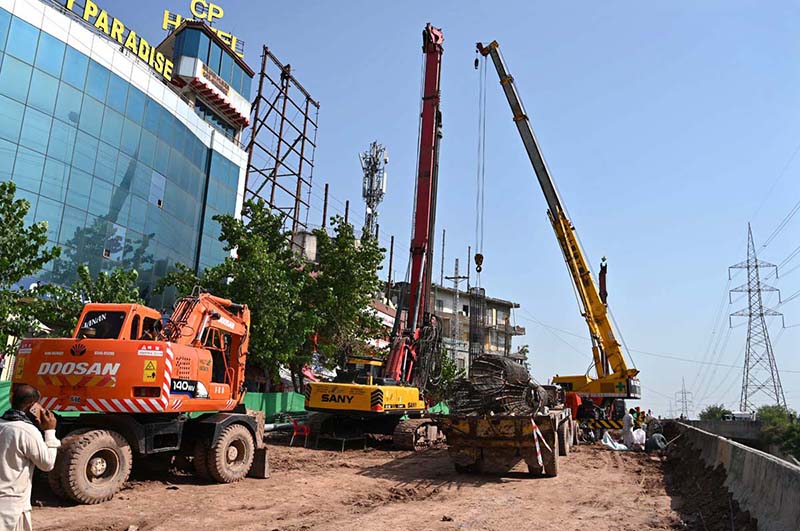 Heavy construction machinery including excavators and cranes are deployed at the service road construction site along the Expressway, as development work continues to improve the road infrastructure in the Federal Capital