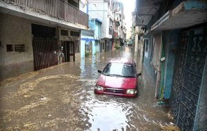 Vehicles navigate through deep floodwater as people wade along a flooded road following heavy monsoon rainfall in Rahimabad area in the City.