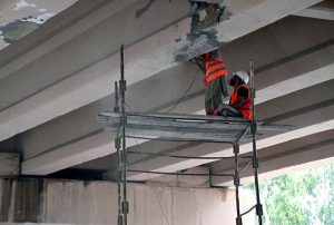 Labourers repair and paint the underside of an overpass along GT Road near Srinagar Highway in the Federal Capital.
