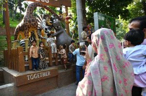 A woman takes photos of children with her mobile phone at the zoo