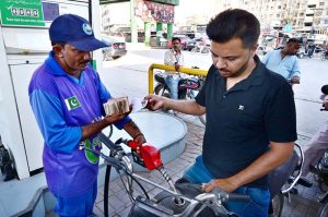 A motorcyclist shows the token to a petrol pump attendant under the Prime Minister’s Fuel Relief Scheme to receive subsidized petrol in Latifabad.