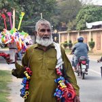 An elderly man strolls through Shadman selling household items and toys to earn a livelihood for his family