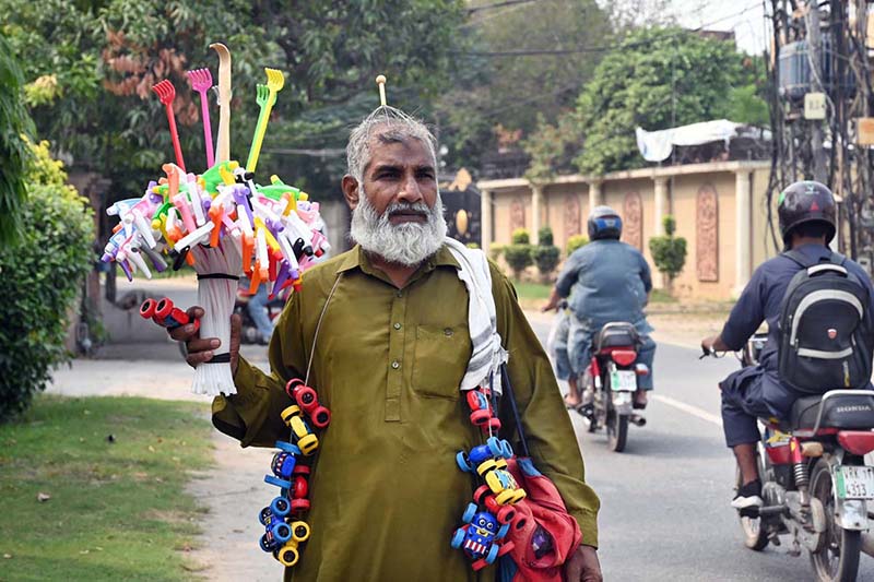 An elderly man strolls through Shadman selling household items and toys to earn a livelihood for his family