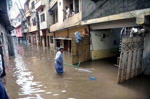 Vehicles navigate through deep floodwater as people wade along a flooded road following heavy monsoon rainfall in Rahimabad area in the City.