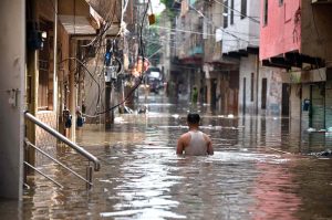 Vehicles navigate through deep floodwater as people wade along a flooded road following heavy monsoon rainfall in Rahimabad area in the City.