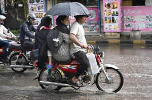 Motorcyclists ride with umbrellas during rain in the provincial capital.