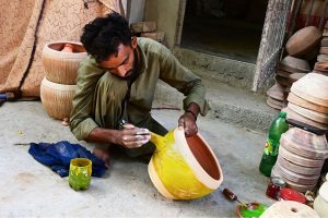 A worker is busy preparing clay-made items at his workplace in Kumhar Pura