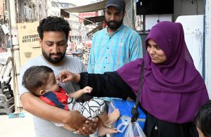 A lady health worker administers polio drops to a child at Patiala Ground Road