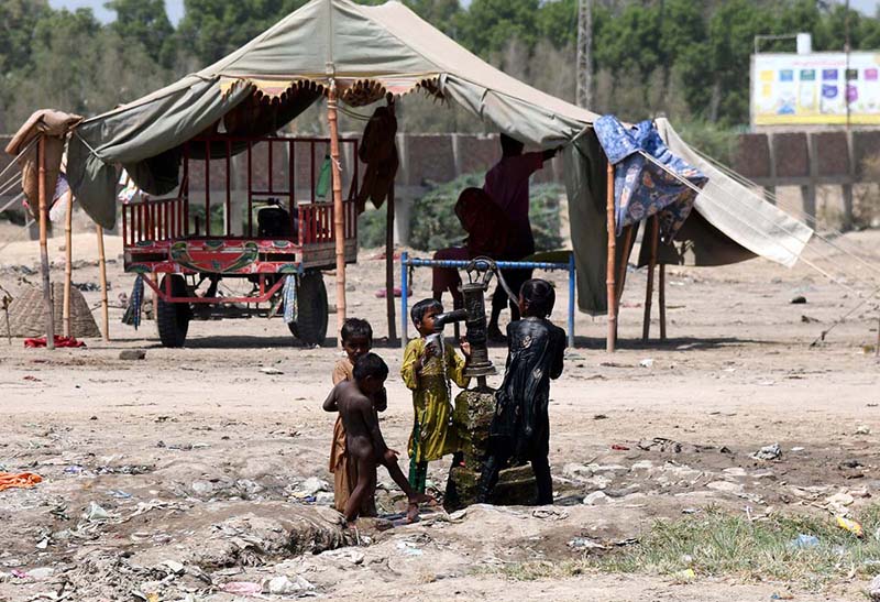 Gypsy children enjoy a bath at a hand pump outside their makeshift huts near Ratodero Bypass