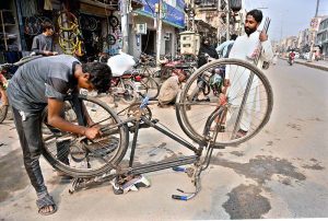 A bicycle mechanic is repairing a bicycle at his workshop in Liaquat Market.