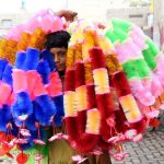 A boy walks through a street carrying artificial garlands