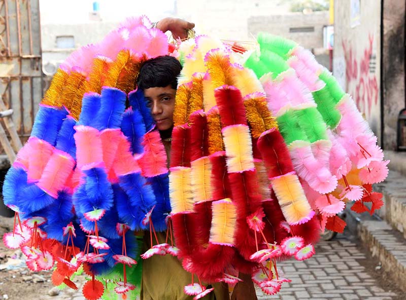 A boy walks through a street carrying artificial garlands