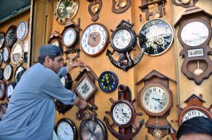 A shopkeeper on Mission Road is arranging wall clocks to attract the attention of passersby for sell.