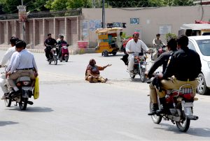 A woman begs on the roadside in front of the Chandka Medical College gate