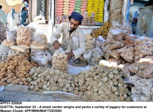 A street vendor weighs and packs a variety of jaggery for customers at Meezan Chowk.