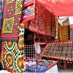 Vendors display colorful handmade traditional patchwork bed sheets for a customer at his shop