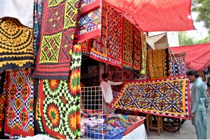 Vendors display colorful handmade traditional patchwork bed sheets for a customer at his shop