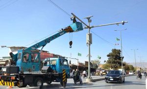 A worker cleans surveillance cameras and solar panels installed under the Safe City project along Joint Road.