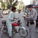 Traffic police personnel issue challans to motorcyclists for violating traffic rules at Manan Chowk