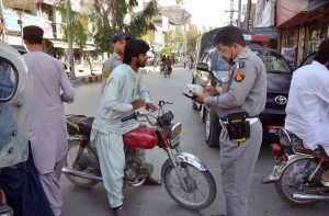 Traffic police personnel issue challans to motorcyclists for violating traffic rules at Manan Chowk