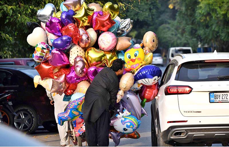 Report: A balloon vendor is trying to persuade a motorist to buy a balloon at Jinnah Supermarket