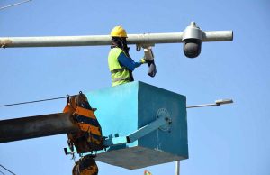 A worker cleans surveillance cameras and solar panels installed under the Safe City project along Joint Road.