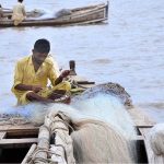 A fisherman prepares a fishing net along the banks of the Indus River as the fishing season begins