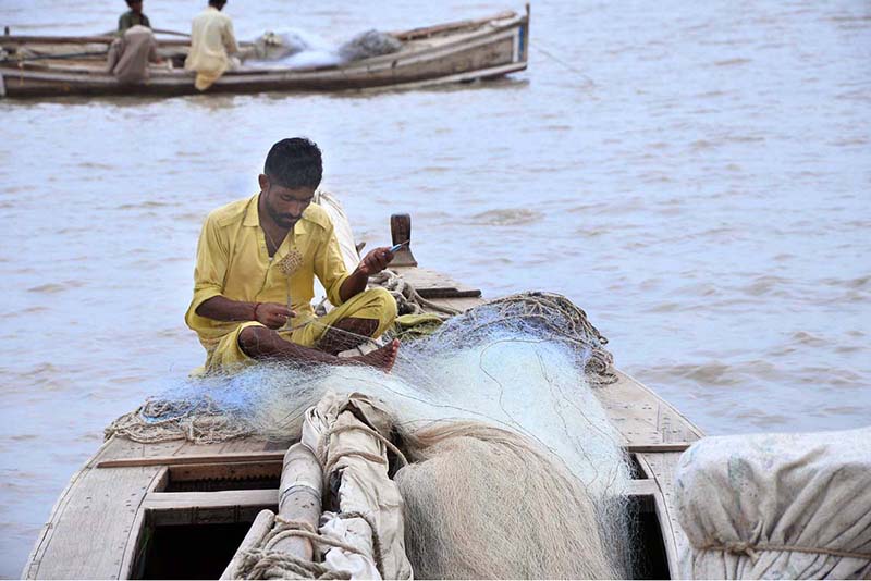 A fisherman prepares a fishing net along the banks of the Indus River as the fishing season begins