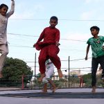 Children enjoying and jumping on trampoline along the roadside setup